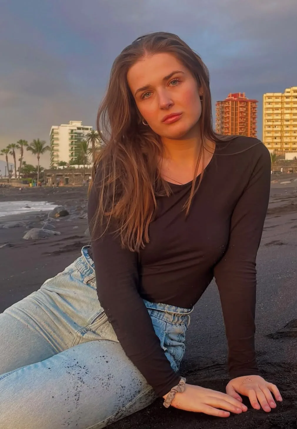 Retrato de mujer sobre arena volcánica al atardecer